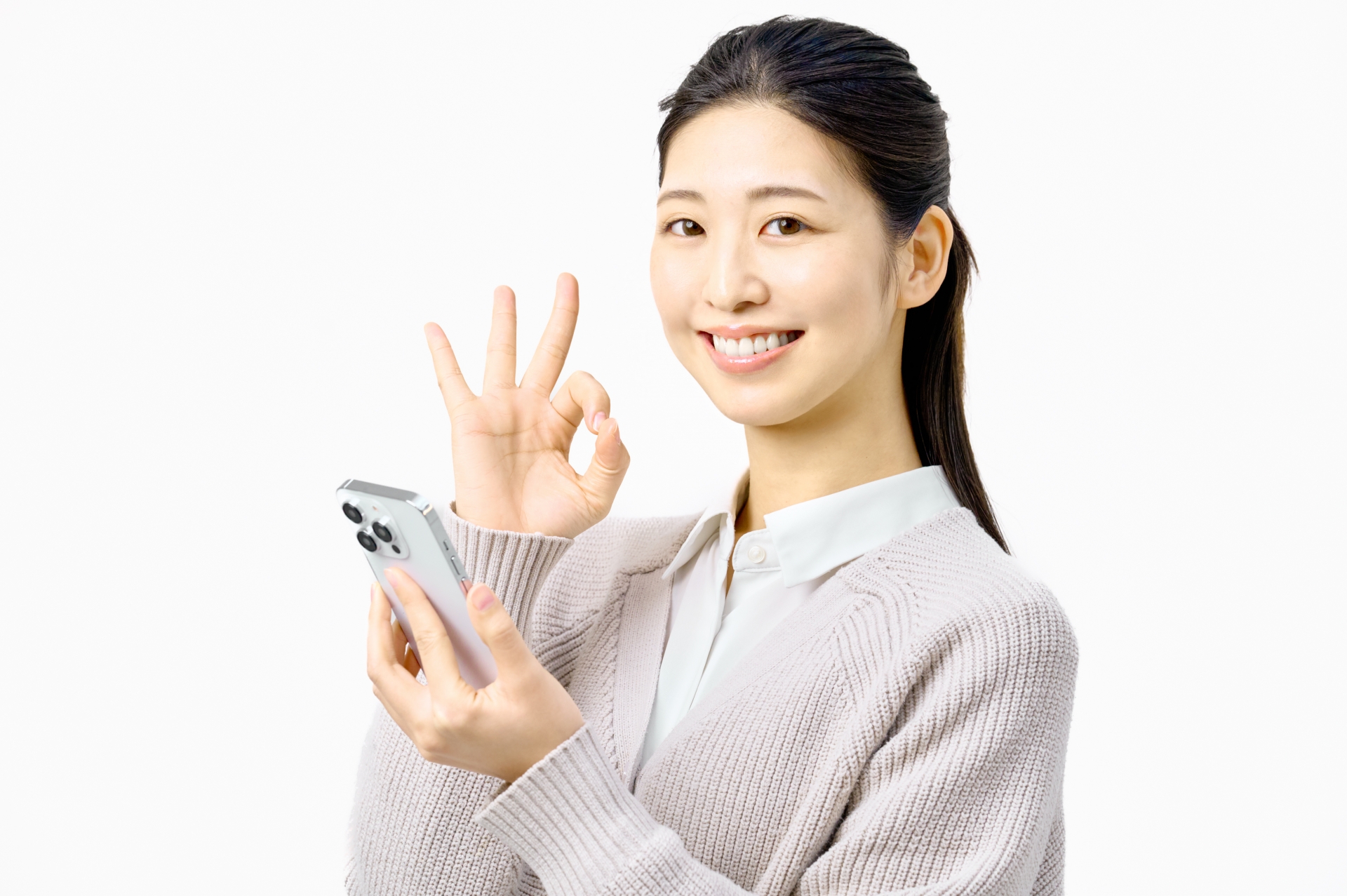 スマートフォンを片手に持ち、笑顔でOKサインを出している女性。スマホで手軽に依頼や解決ができるイメージ